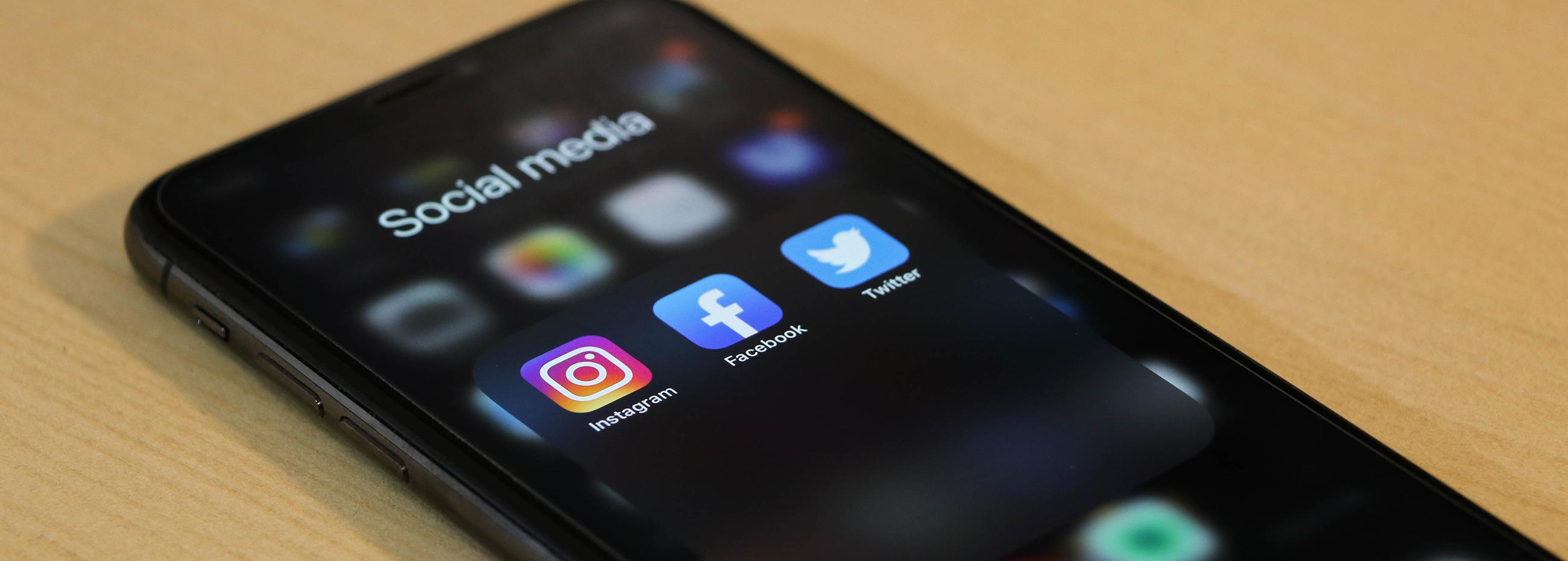 Illustreeriv foto iPhone'ist, kus on avatud sotsiaalmeediakanalite menüü ning seal on näha Instagrami, Facebooki ja Twitteri ikoone.
