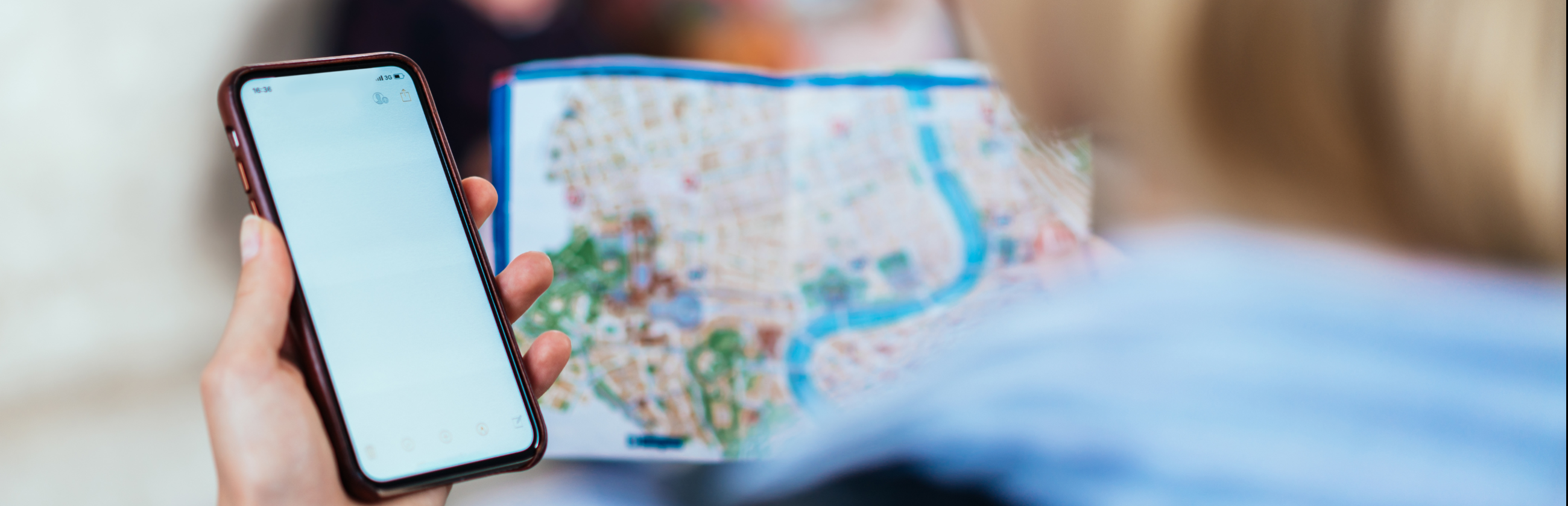 Telefon käes, kaardiga linnas orienteerumine